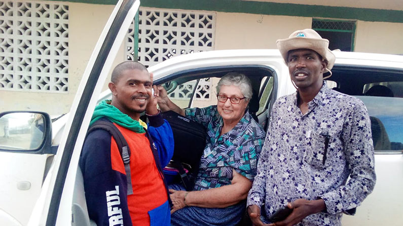 Global worker with two Kenyan men at eye clinic