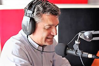 photo of man wearing headphones and speaking into microphone
