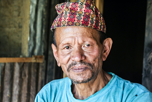 photo of Nepali man wearing blue shirt and striped hat