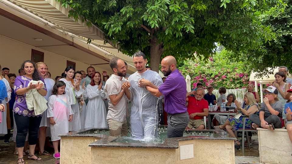 photo of Turkish man being baptized outdoors with church members looking on
