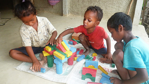 photo of three Nepalese children playing with blocks