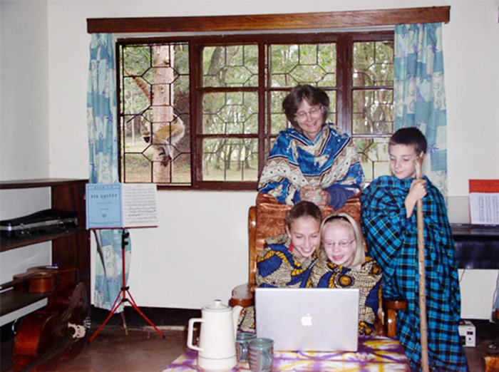 Photo of children and mom with laptop, with monkey looking in window