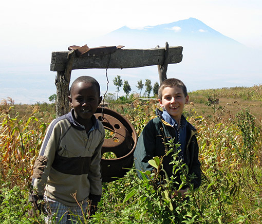 photo of Tanzanian boy and American boy standing in field with mountain in background