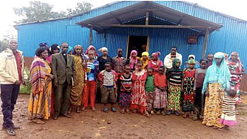 men and women standing in front of church in Kenya with blue walls
