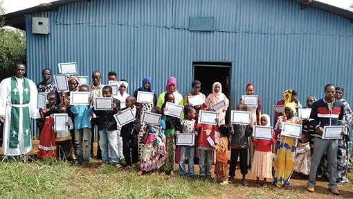 group of people in Kenya standing in front of blue building holding white certificates