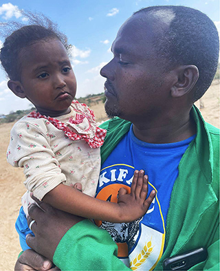 African man holding frowning child