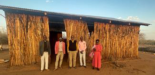 five people standing in front of primitive church in Kenya