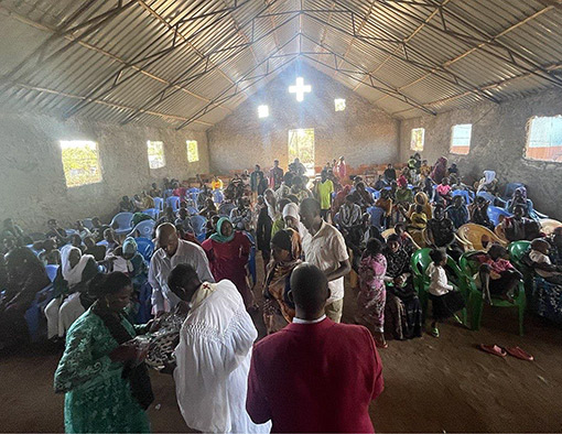 group of people taking communion inside primitive church in Kenya