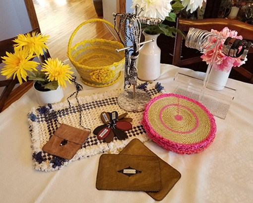 display of woven baskets and placemats on table with vases of flowers and handmade leather gifts