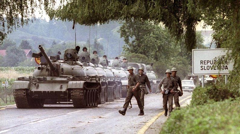 soldiers walking on road beside of tanks