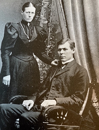 vintage wedding photo of woman standing with hand on shoulder of seated husband