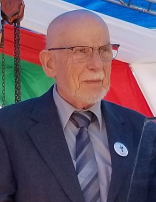 man with white beard and mustache wearing blue suit and striped tie