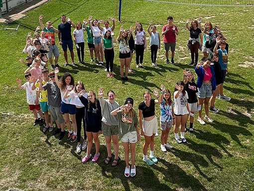 young people standing in heart-shaped formation on grassy sports field
