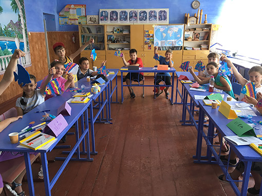 students seated at blue tables in classroom