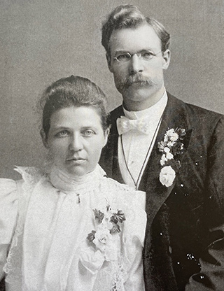 vintage wedding photo of woman in white dress, man with mustache wearing dark suit, white shirt and white bow tie