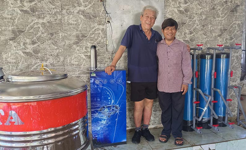 man and woman standing in front of water filtration system in Vietnam