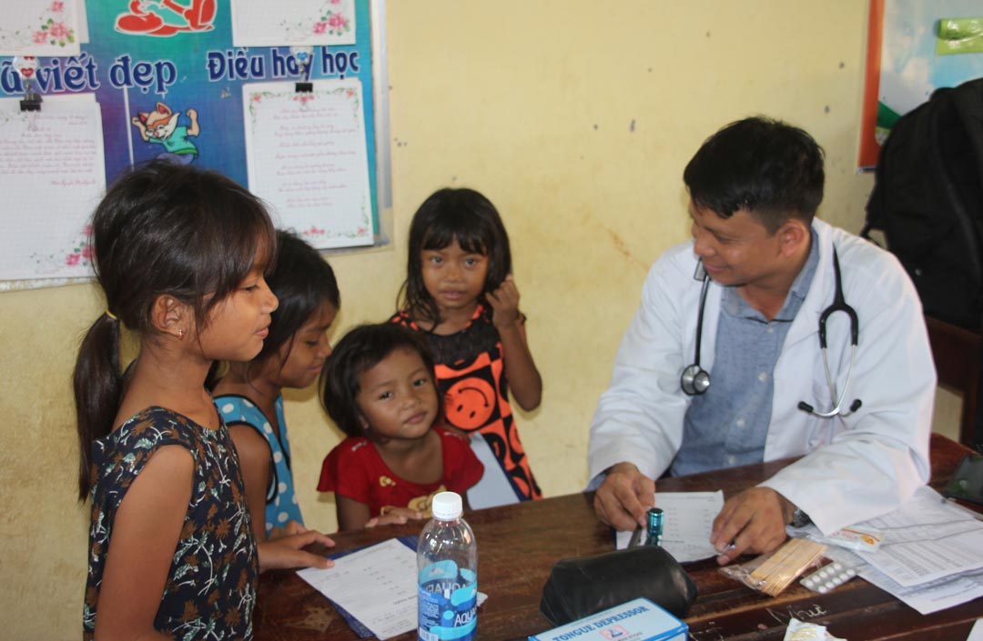 Vietnamese doctor talking with 4 young girls at clinic