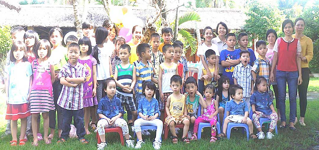 group photo of Vietnamese children and adults standing outside on lawn