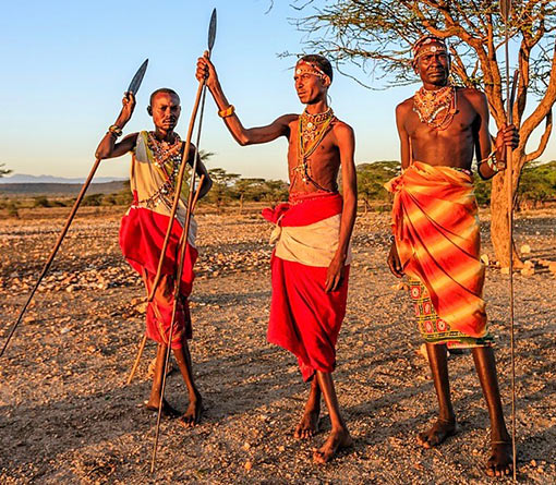 3 Sambru warriors holding spears, wearing colorful clothing and neck ornaments