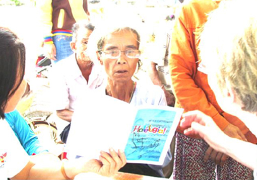 Vietnamese woman wearing new glasses reading pamphlet