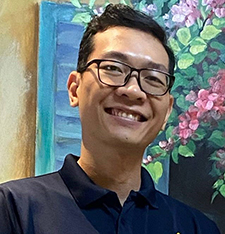headshot of Vietnamese man wearing glasses and black shirt