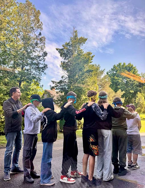 group of youth in line with hands on shoulders of person in front