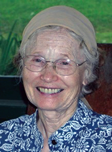 older lady with gray hair and glasses wearing blue print blouse