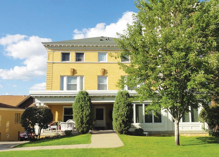 large yellow house with sidewalk and tree in front
