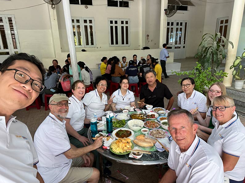 group of people wearing white shirts seated at round table for a meal