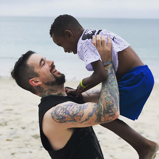 man lifting smiling boy at beach