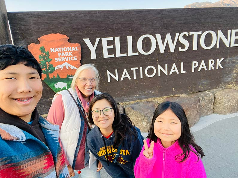 group of people standing by Yellowstone National Park sign