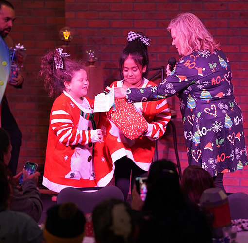 woman giving gifts to two girls at Christmas Festival