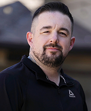 headshot of man with dark hair and beard wearing black shirt
