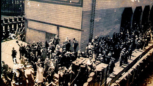 vintage photo of crowd standing on dock as ship embarks