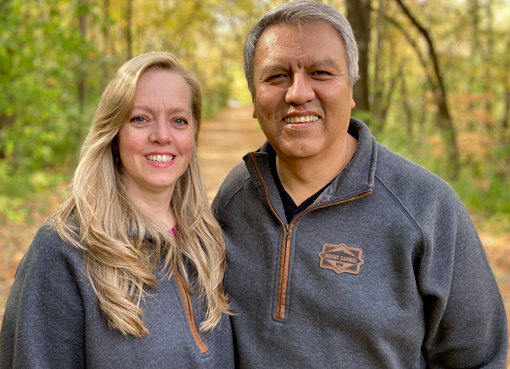woman with long blond hair standing beside man with gray hair wearing matching shirts