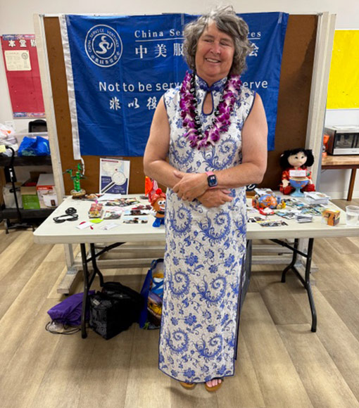 woman wearing chinese dress standing in front of display table and chalkboard