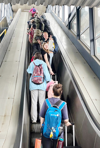 girls wearing backpacks riding on escalator