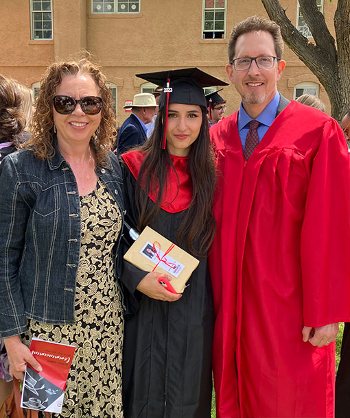 pastor and wife posing for photo with high school graduate